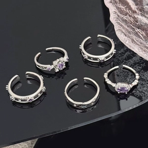 Detail shot of five silver rings set with purple zircon gemstones on reflective black base