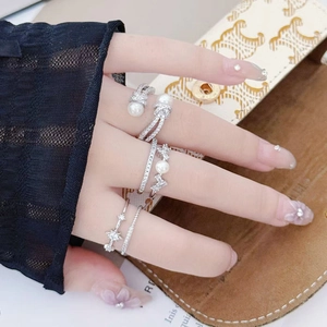 Close-up of three silver rings set with pearls and zircons on a hand with lace detail
