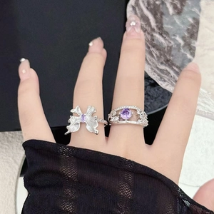 Detail shot of silver bow ring and open band set featuring purple zircon gemstones