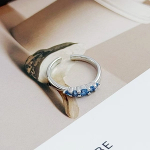 Detail view of adjustable silver ring with five round blue zircons in prong setting