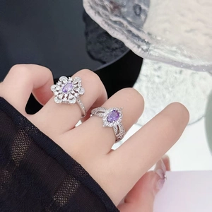 Detailed view of silver rings featuring purple zircon flower and oval shapes on finger