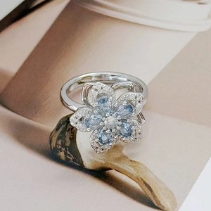 Macro detail of the silver flower ring featuring blue pear-cut zircon petals and micro pavé