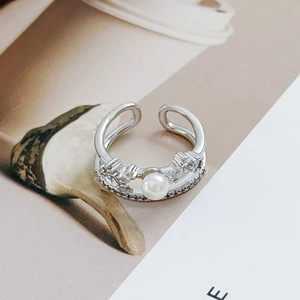 Detailed macro of a silver double-layered open ring with pearl and crown elements