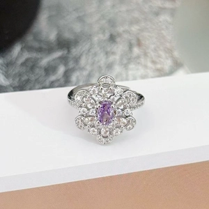 Close-up of a floral silver ring with an oval purple gemstone and pavé diamond halo