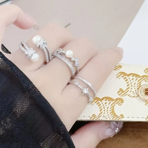 Detailed view of silver rings featuring pearls, crown design and star charms on hand