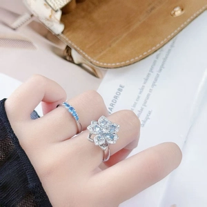 Detail of silver floral ring set with light blue zircon stones on a female hand