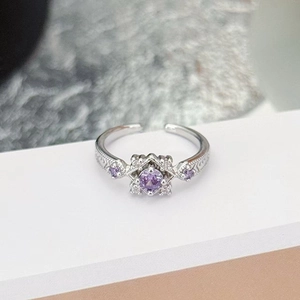 Close-up of vintage style silver ring featuring a round purple zircon and engraved band