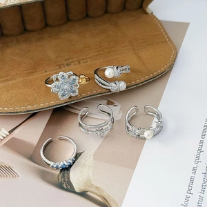 Detail of silver-toned flower ring set with blue zircon and pearls on brown suede box