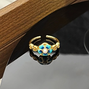 Detailaufnahme von Vintage-Ring mit blauer Blume, Perle und goldener Metallverzierung