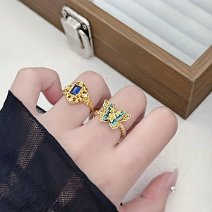 Detailansicht von Vintage-Schmetterlings-Emaille-Ring und blauem Edelsteinring am Finger
