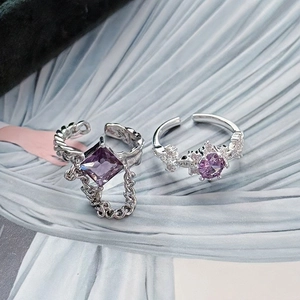 Detailed shot of two silver adjustable rings with purple gemstones and chain accents