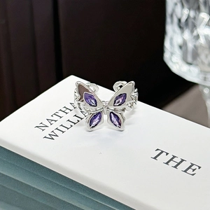 Macro shot of silver butterfly ring with purple marquise gemstones and chain texture