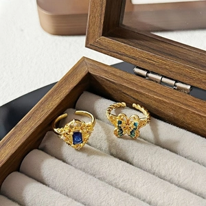 Detailansicht eines Vintage-Schmetterlingsrings und blauen Kristallrings in einer Holzbox
