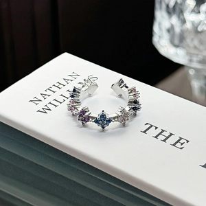 Macro detail of silver-tone ear cuff with colorful star-shaped zirconia on white book
