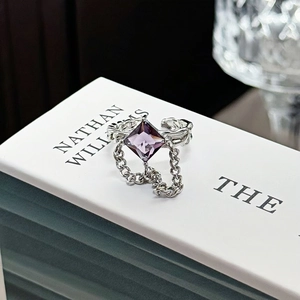 Detail of square purple gemstone ring with metal chains and textured silver band