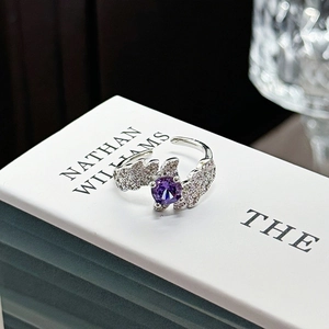 Detail of silver open ring with purple gemstone and sparkling diamond-set wings