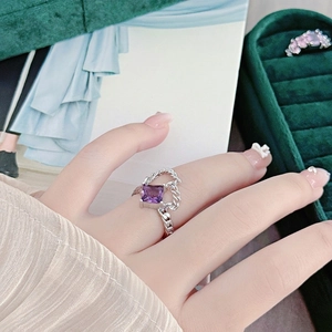 Close-up of a silver twist ring with a square purple gemstone on a finger