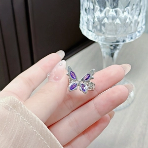 Close-up of a silver butterfly open ring featuring four purple marquise-cut crystals