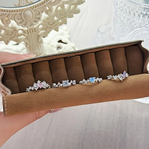 Detail of four butterfly and floral zircon rings organized in a brown suede jewelry roll