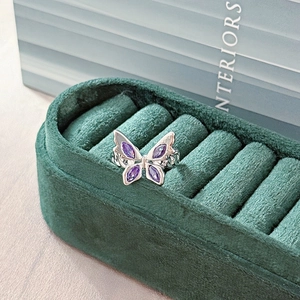 Close-up of butterfly ring with purple crystals in a green velvet jewelry box