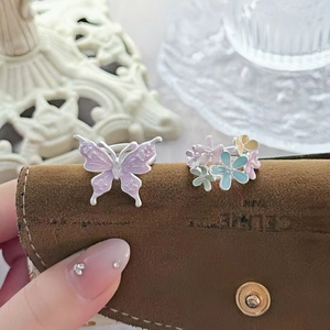 Detailed macro view of lavender enamel butterfly and multi-color floral open ring set