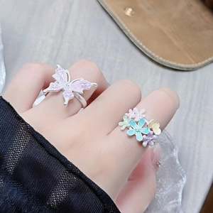 Detail view of butterfly and floral enamel open rings with zircon stones on model hand
