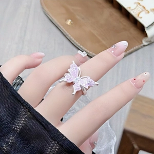 Close-up of a butterfly zircon open ring with pink enamel detail worn on the finger