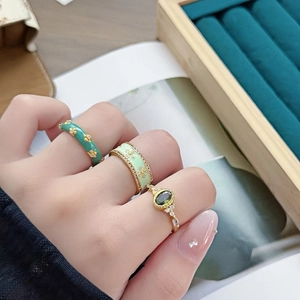 Détail d'un ensemble de trois bagues fleur en émail vert et émeraude sur un mannequin
