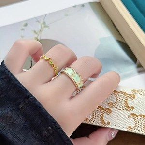 Détail de bagues en émail vert menthe aux motifs floraux portées avec un style élégant