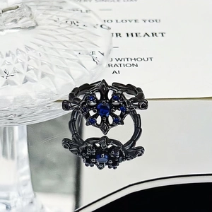 Macro shot of a dark punk ring with a blue crystal center and snowflake metal engraving