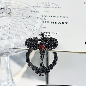 Detail of gothic rose relief ring featuring a red heart gem and black metal cross