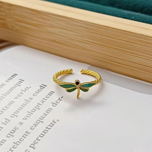 Vue détaillée d'une bague libellule dorée avec ailes en émail vert et anneau torsadé