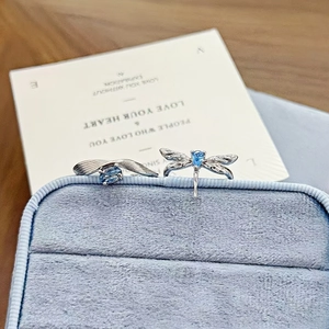 Close-up of elegant dragonfly ring and wavy band with blue pear-shaped zircon stones