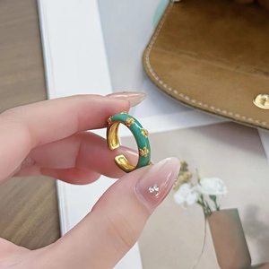 Détails d'une bague fleur en émail vert menthe avec bordure dorée et incrustations