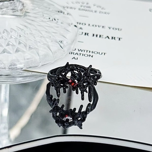 Macro detail of gothic thorn ring in black finish with a ruby red gemstone accent