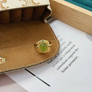Vue détaillée de la bague dorée vintage avec pierre verte et gravure florale en relief