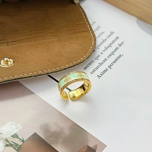Gros plan sur la bague large en émail vert menthe avec motifs d'étoiles dorées réglable