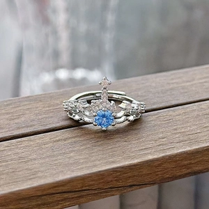 Macro shot of silver crown ring featuring a blue gemstone and white zircon accents