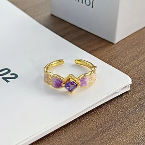 Nahaufnahme eines goldenen Vintage-Rings mit lila Edelstein und Emaille-Blütenblättern