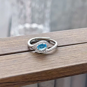 Close-up of adjustable silver ring with oval blue gemstone and cubic zirconia accents