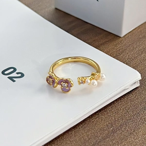 Detail eines lila Emaille-Blumenrings mit Perlen und verstellbarem Goldband