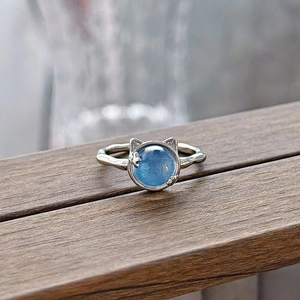 Macro detail of cat-ear silver ring with round blue gemstone and textured band