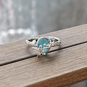 Detailed macro view of the teardrop-shaped blue gemstone and vine-inspired silver ring band