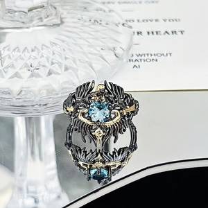 Macro shot of gothic ring featuring sky blue gemstone and black gold dragon scale carving