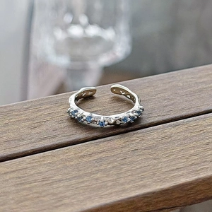 Macro detail of silver adjustable ring featuring blue zircon stones and hollow heart