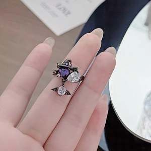 Detail of dark punk Halloween ring with purple heart gem and bat wing wizard hat charm