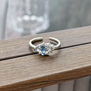 Detailed shot of an adjustable silver ring with blue oval gemstone on a wood beam