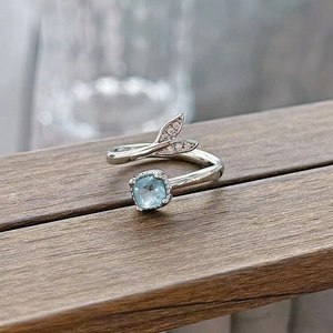 Close-up of aquamarine square stone and diamond-set fishtail on an adjustable silver ring