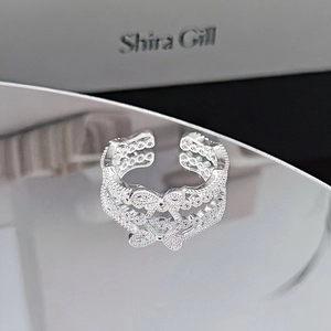 Detailed view of silver bow-shaped open ring with cubic zirconia and wavy band