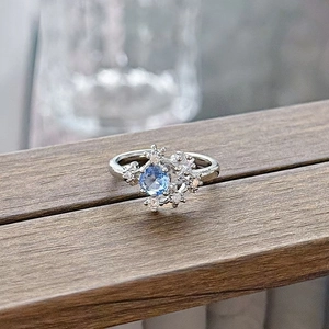 Detail of light blue gemstone ring with snowflake pattern on dark wood surface
